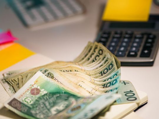 Polskie banknoty i kalkulator na biurku – zdjęcie ilustracyjne